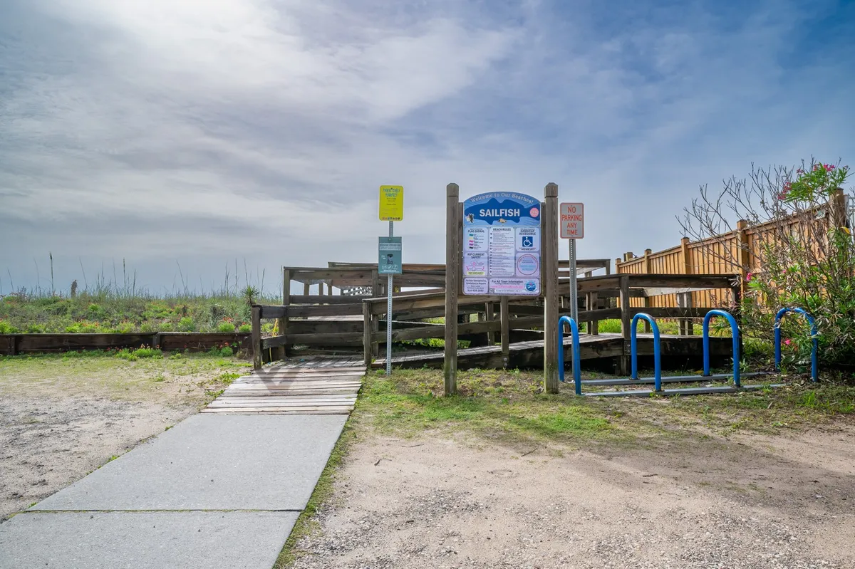 A welcoming exterior shot featuring an access ramp, an information sign, a bicycle rack, and lush greenery, capturing the accessibility and relaxed outdoor vibe of local gathering spots. The setup emphasizes easy, active exploration by bike or on foot.
