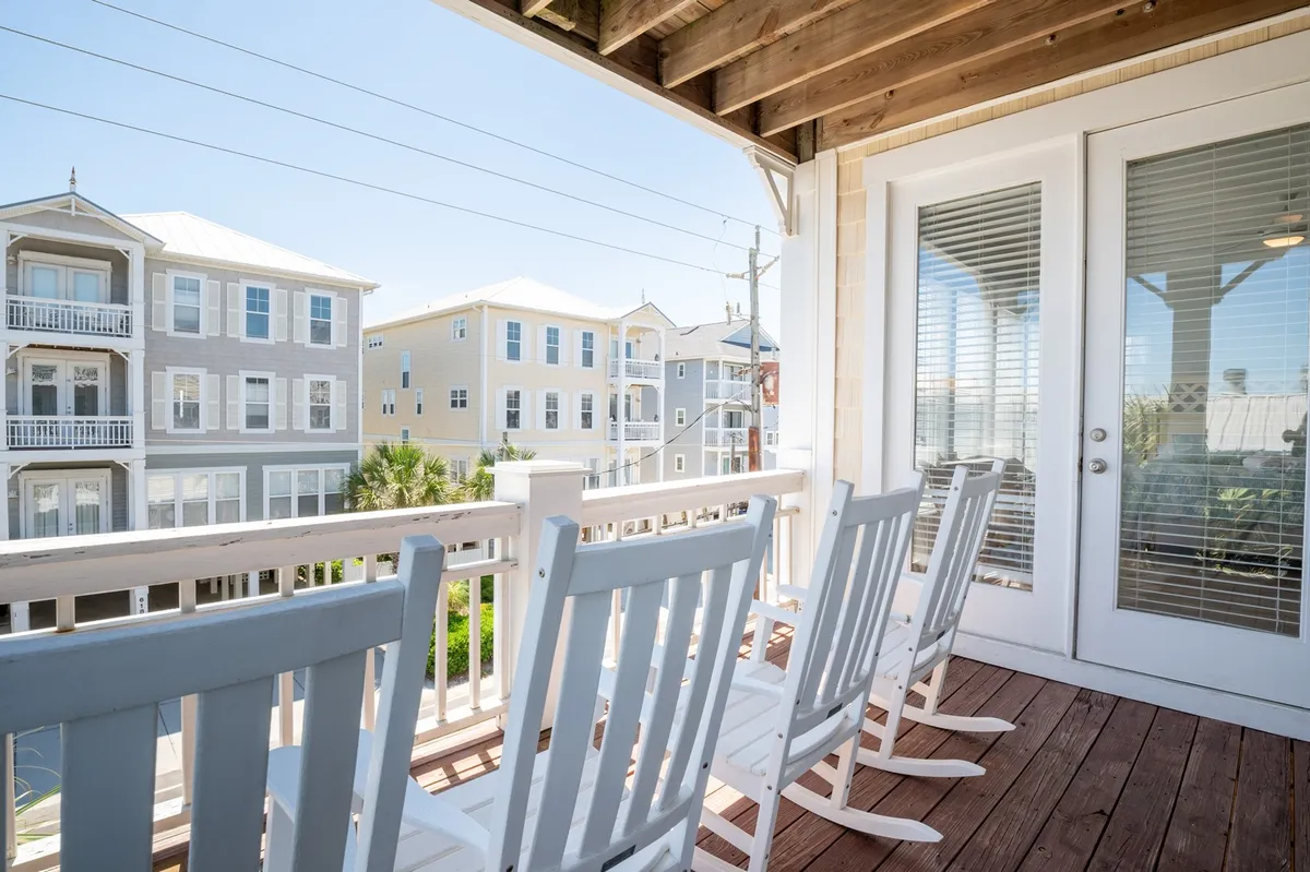 A tranquil porch setting with classic rocking chairs facing neighboring buildings, ideal for relaxing after a day of exploration. The scene suggests a welcoming home base, blending relaxation and connection to the neighborhood.