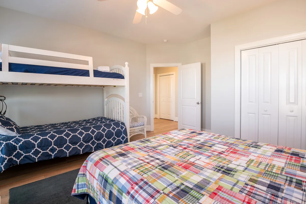 A cheerful family suite with a sturdy bunk bed featuring plaid bedding and a cozy lounge chair nearby. The room is bathed in natural light, creating a friendly, playful mood perfect for children or family groups.