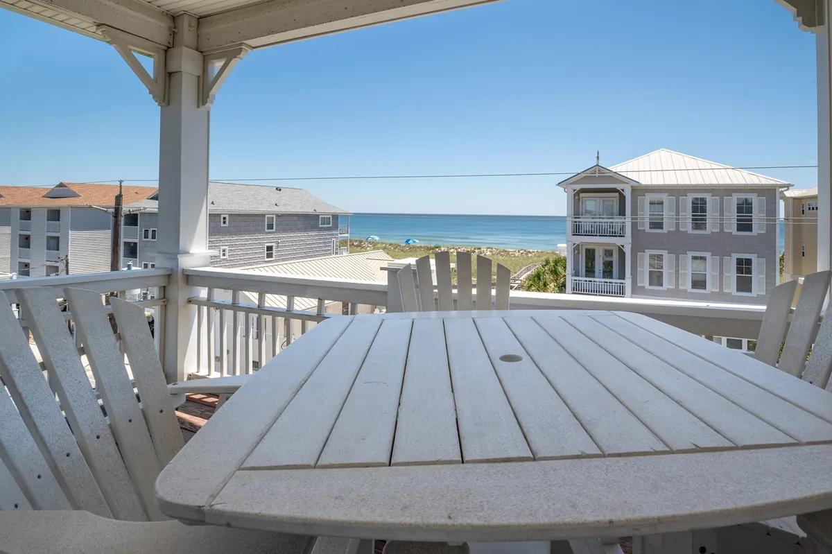 An inviting oceanview deck with comfortable outdoor seating, looking out towards the water and neighboring homes. The setting is perfect for al fresco dining, sunset cocktails, or simply enjoying fresh ocean breezes with good company.