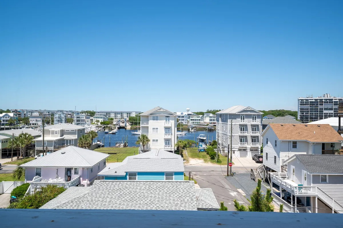A panoramic view of the waterfront lined with houses and boats under a clear sky. The scene conveys a peaceful neighborhood with ample opportunities for exploration, community events, and water-based recreation.