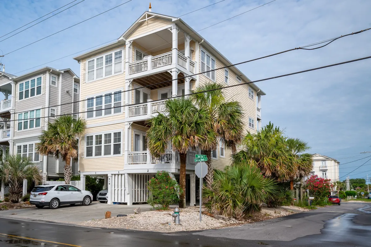 The hero image showcases a spacious, multi-level family townhouse surrounded by swaying palm trees and lush greenery. The home’s balconies offer inviting spaces for ocean breezes and sunset views, while the peaceful street and welcoming porch set the stage for memorable outdoor gatherings.